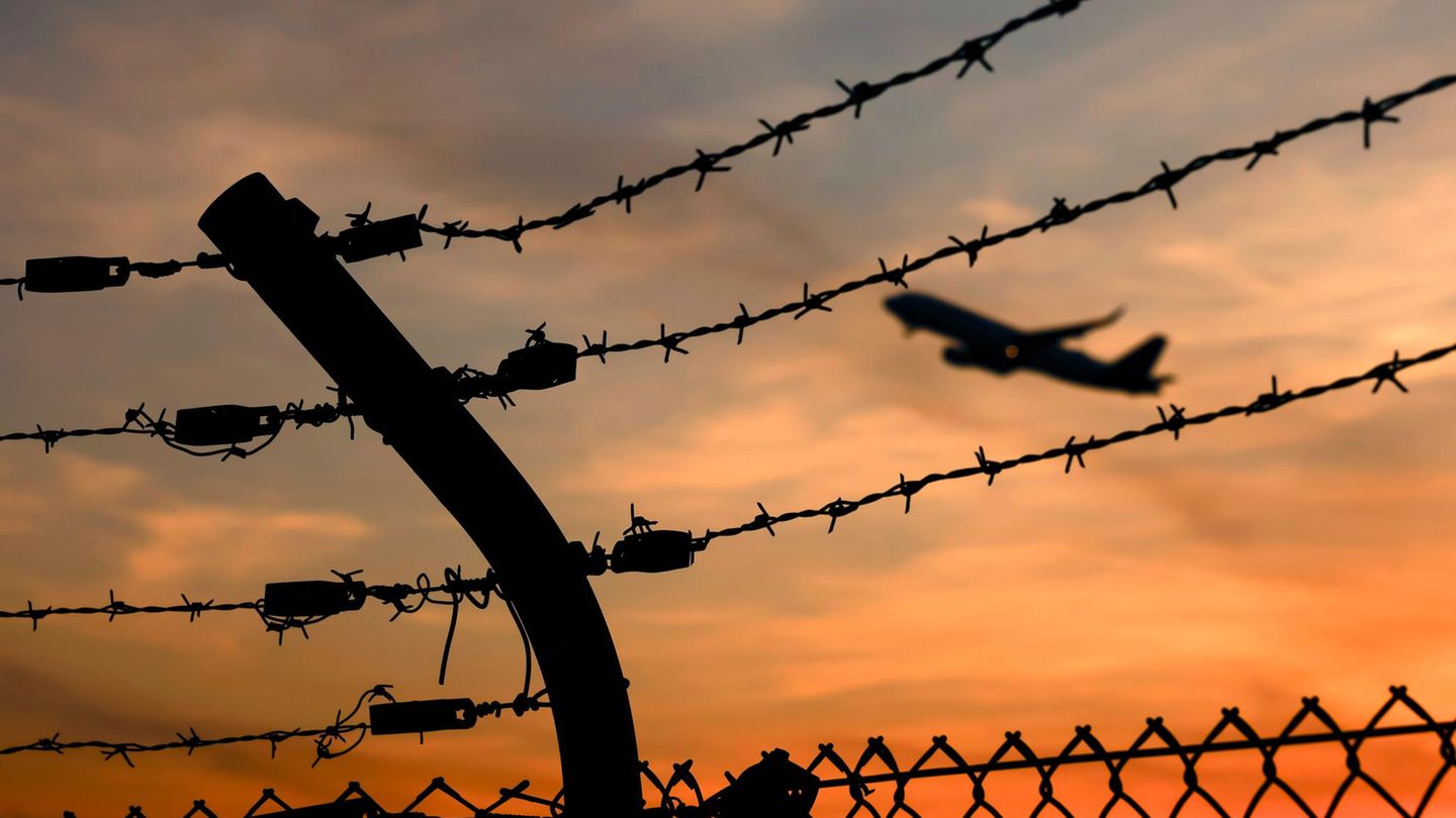 Abschiebungen Symbolbild Abschiebungen: Ein Flugzeug hebt ab, durch einen Stachedrahtzaun fotografier