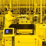 Ein Mann in weißer Reinraumkleidung arbeitet mit Augmented Reality Brille an einer Prüfmaschine für Chips