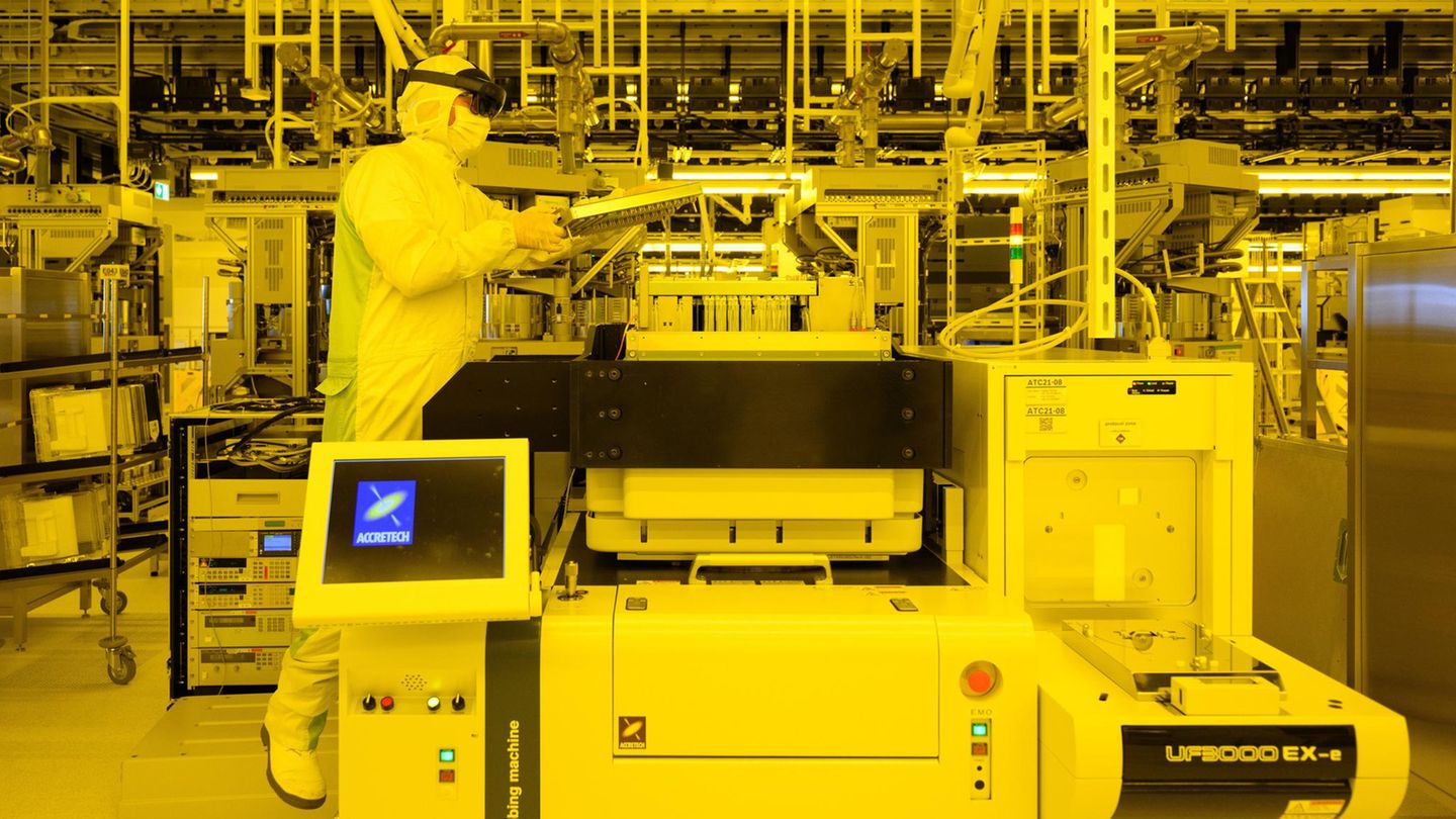 Ein Mann in weißer Reinraumkleidung arbeitet mit Augmented Reality Brille an einer Prüfmaschine für Chips