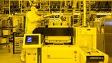 Ein Mann in weißer Reinraumkleidung arbeitet mit Augmented Reality Brille an einer Prüfmaschine für Chips