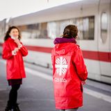 Zwei Frauen in Caritas-Windjacken stehen in Essen vor einem ICE am Bahnhof und warten auf ankommende Ukrainer