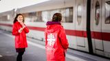 Zwei Frauen in Caritas-Windjacken stehen in Essen vor einem ICE am Bahnhof und warten auf ankommende Ukrainer