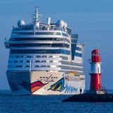 Die "AIDAmar" neben einem Leuchtturm an der Ostsee vor Warnemünde