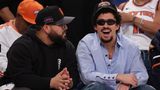 Der Rapper Bad Bunny sitzt mit schwarzer Sonnenbrille und New York Knicks-Cap in der ersten Reihe