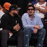 Der Rapper Bad Bunny sitzt mit schwarzer Sonnenbrille und New York Knicks-Cap in der ersten Reihe