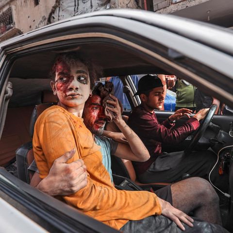 A blood smeared girl sits in a car in Gaza with injured men