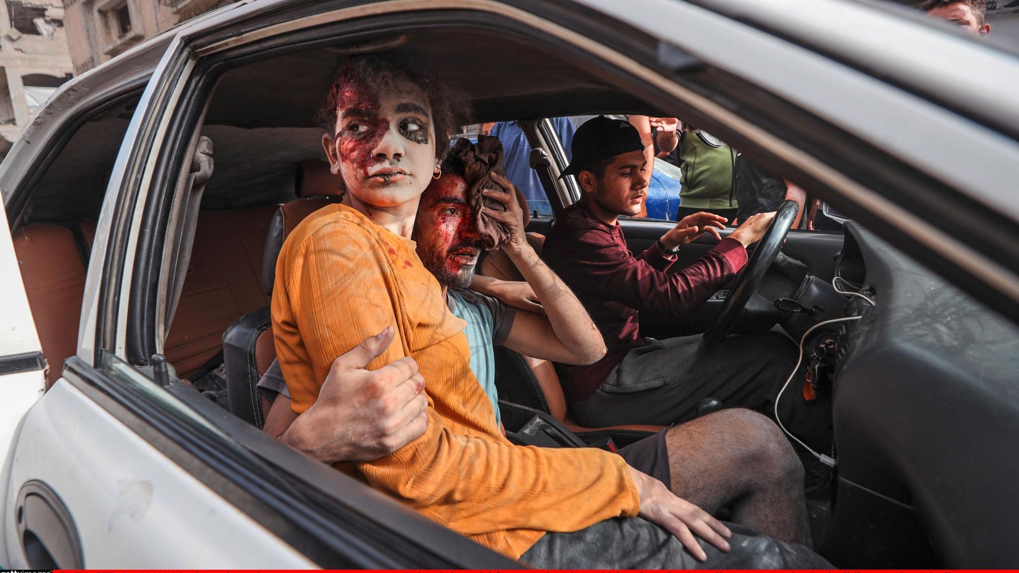 ein Blutverschmiertes Mädchen sitzt mit verletzten Männern in einem Auto in Gaza