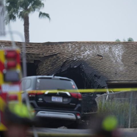 After the crash of a small aircraft in San Diego, the roof of a residential building is pressed in and charred