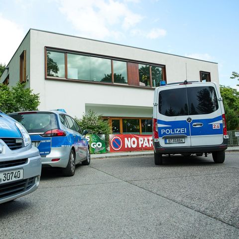 Drei Autos der Polizei Berlin stehen vor einem weißen Schulgebäude