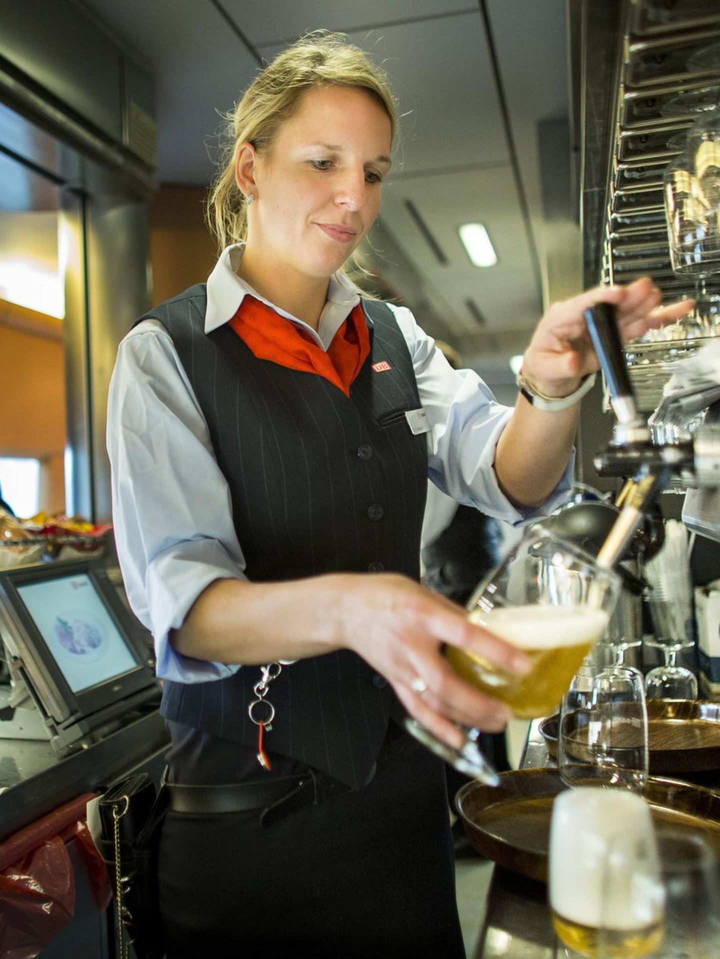 Eine Bahn-Mitarbeiterin zapft im Bordbistro ein Bier (Symbolbild)