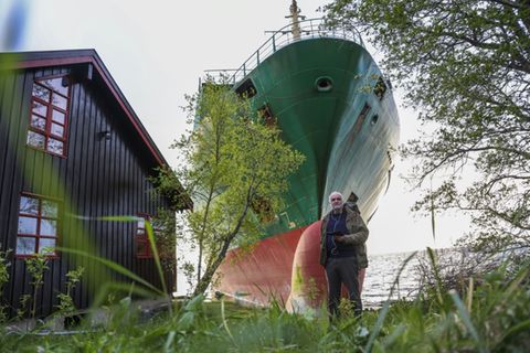 Johan Helberg vor seinem Haus und dem Containerschiff