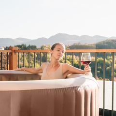 Mid-adult woman is relaxing in a hot tub in a sunny autumn day