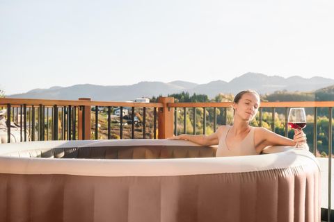Mid-adult woman is relaxing in a hot tub in a sunny autumn day