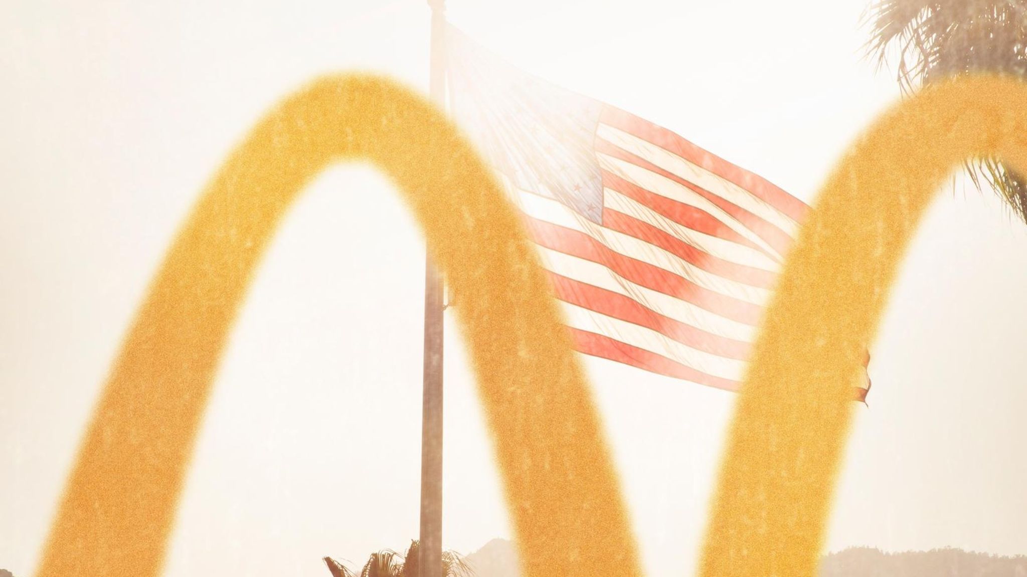 Im Vordergrund ein McDonalds Logo, im Hintergrund eine USA Flagge