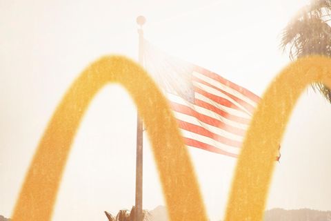 Im Vordergrund ein McDonalds Logo, im Hintergrund eine USA Flagge