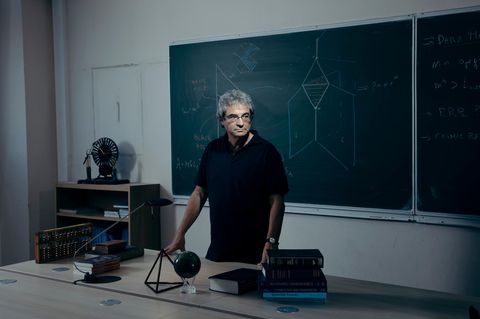Ein Mann in einem schwarzen T-Shirt steht vor einer Tafel