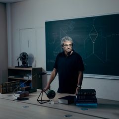 Ein Mann in einem schwarzen T-Shirt steht vor einer Tafel