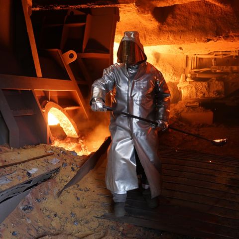 Forsa. Mann mit Schutzanzug in Stahlwerk