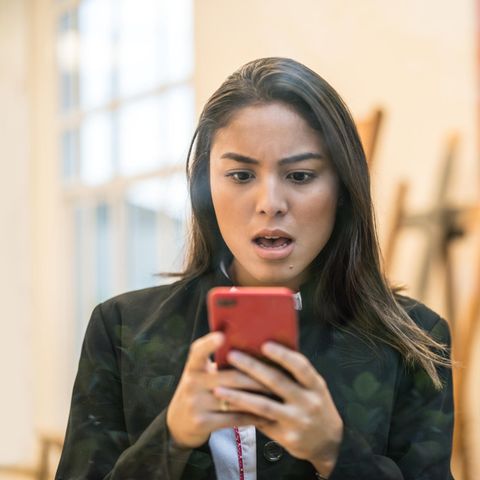 Eine junge Frau schaut erstaunt auf ihr iPhone