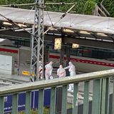 Fünf Personen in weißen Schutzanzügen auf einem Gleis des Hamburger Hauptbahnhofs