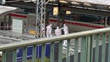 Fünf Personen in weißen Schutzanzügen auf einem Gleis des Hamburger Hauptbahnhofs