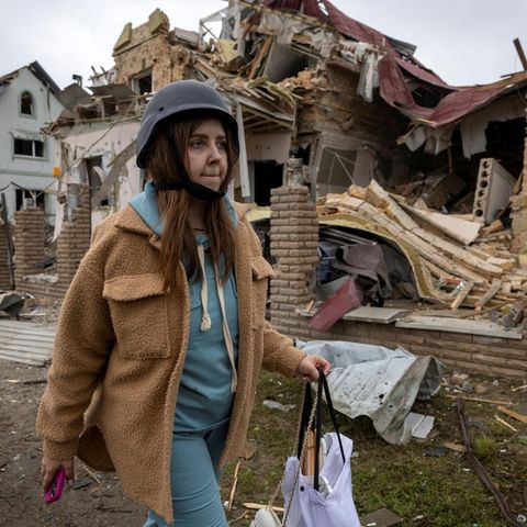 Russland greift Ukraine massiv aus der Luft an: Frau läuft am Morgen danach mit Helm durch zerstörtes Markhalivka bei Kiew