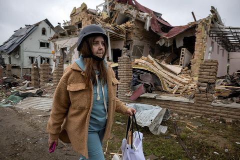 Russland greift Ukraine massiv aus der Luft an: Frau läuft am Morgen danach mit Helm durch zerstörtes Markhalivka bei Kiew