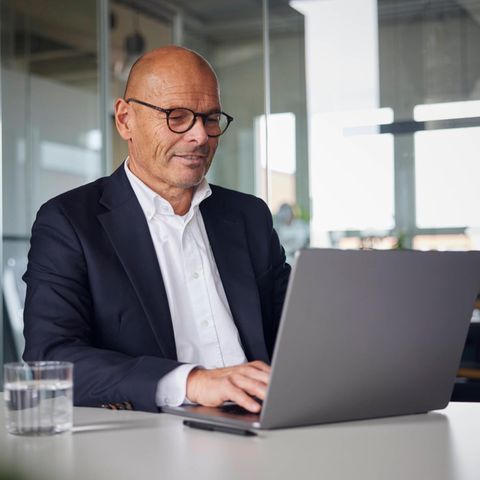 Geschäftsmann sitzend und mit Laptop im Büro