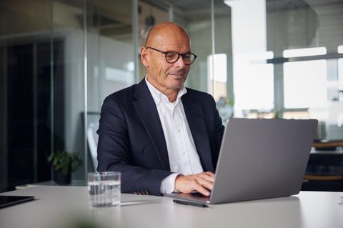 Geschäftsmann sitzend und mit Laptop im Büro