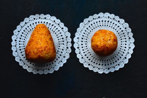 Arancini con tonno e melanzane  Gefüllte Reisbällchen mit Thunfisch und Auberginen  Ergibt etwa 12 Stück | Zubereitungszeit: 1 Stunde 20 Minuten, plus Kühlzeit  Wussten Sie schon? In Palermo heißen die Reisbällchen "Arancina" (weiblich und rund), in Catania "Arancino" (männlich und spitz). Wer das verwechselt, outet sich sofort als Tourist!     Für den Reismantel:500 g Arborio-Reis4 EL frisch geriebener Pecorino siciliano4 EL frisch geriebener Parmesan2 TL Currypulver100 g Weizenmehl (Type 405)160 g mollica secca (Paniermehl), fein geriebenGrobes MeersalzSchwarzer Pfeffer  Für die Füllung:Olivenöl extra vergine220 g Auberginen, 1,5 cm groß gewürfelt180 g Thunfischfilet, 1,5 cm groß gewürfelt1 Zwiebel, in Streifen geschnitten350 g stückige Tomaten (Dose)2 EL gehackte Basilikumblätter2 EL gehackte Minzeblätter100-120 g Provolone, gewürfeltPeperoncinoflockenNeutrales Frittieröl  Zubereitung:Reis in gesalzenem Wasser al dente kochen. Noch warm mit Käse und Currypulver mischen, 1 Stunde kühlen.Auberginen in Olivenöl anrösten. Thunfisch salzen, mehlieren und kurz anbraten.Zwiebel goldgelb braten, Tomaten, Kräuter und Gewürze zugeben, einkochen lassen. Thunfisch und Auberginen unterziehen.Aus Reis Kugeln formen, mit Füllung und Käse befüllen, verschließen.In Mehl-Wasser-Mischung und Paniermehl wenden.Bei 180°C goldbraun frittieren.   
