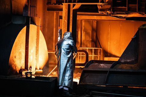 Ein Arbeiter im Schutzanzug nimmt eine Probe vom Stahlabstich.