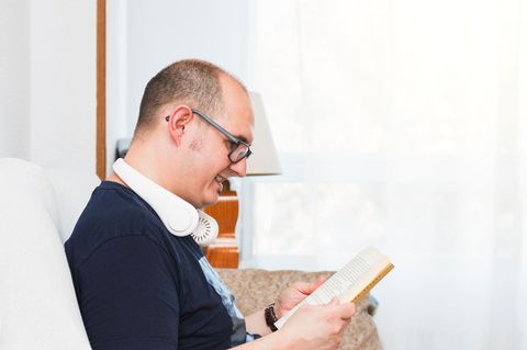 Ein glatzköpfiger Mann mit einem Nackenkühler beim Lesen