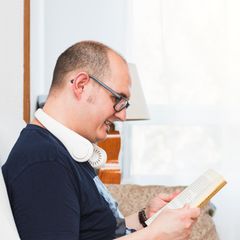 Ein glatzköpfiger Mann mit einem Nackenkühler beim Lesen