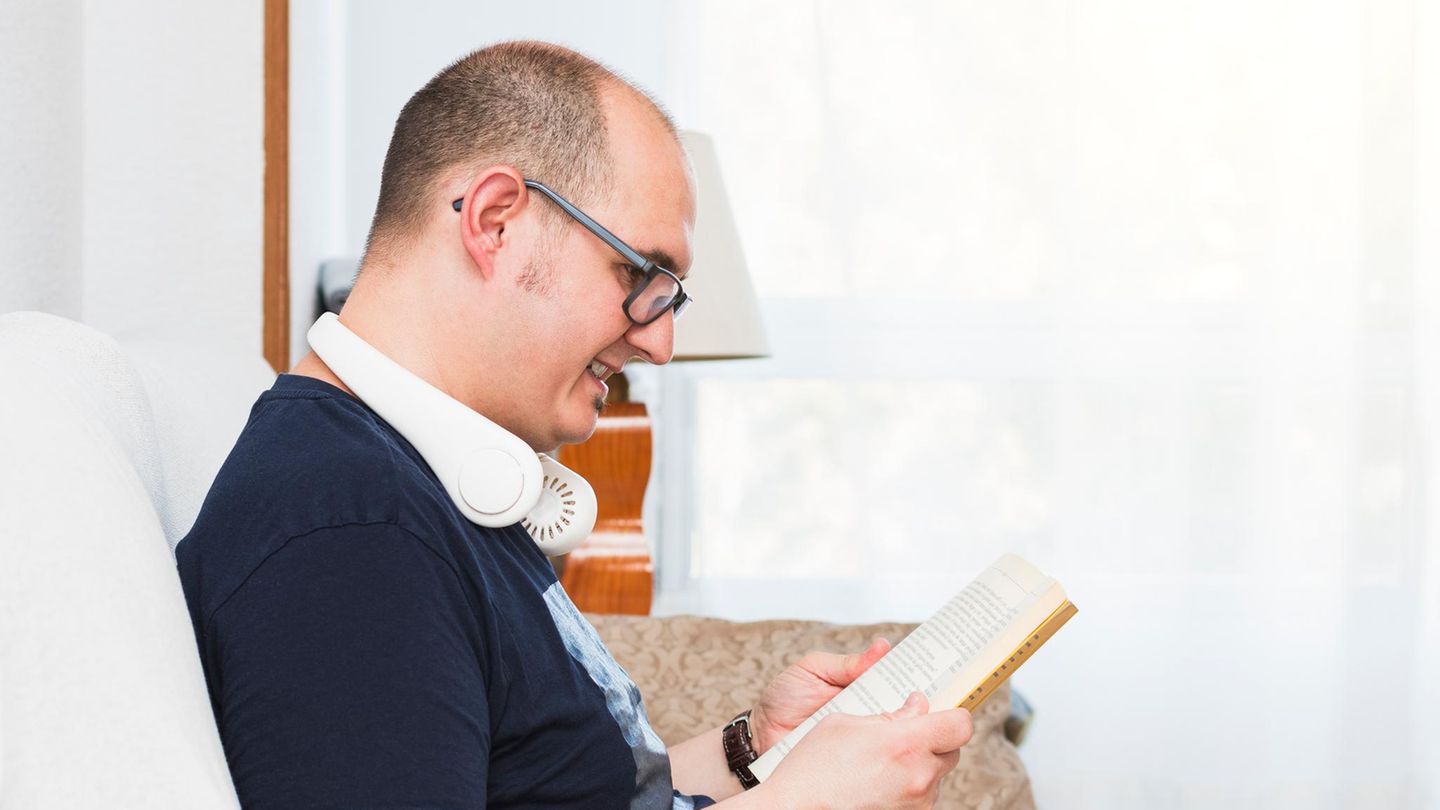 Ein glatzköpfiger Mann mit einem Nackenkühler beim Lesen