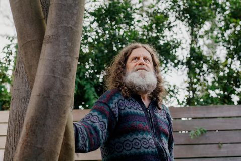 Neurowissenschaftler Robert M. Sapolsky steht leicht angelehnt an einem Baum