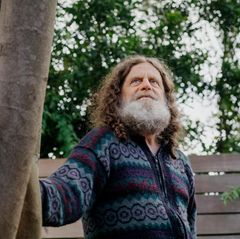 Neurowissenschaftler Robert M. Sapolsky steht leicht angelehnt an einem Baum