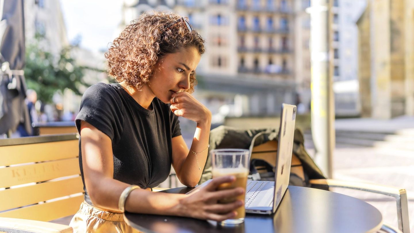 Griechenland Geschäftsfrau trinkt Kaffee auf einer Terrasse und arbeitet mit einem Laptop