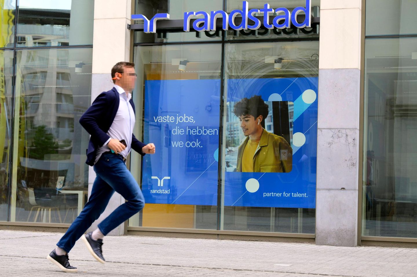 A man runs past a shop window of the temporary employment agency Randstad