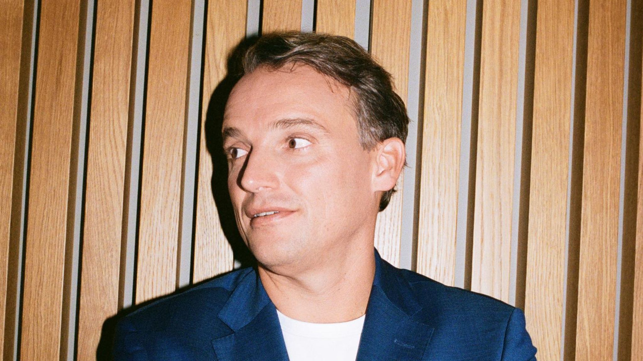 Christian Klein steht mit verschränkten Armen vor einer Wand