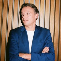 Christian Klein steht mit verschränkten Armen vor einer Wand