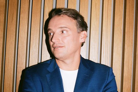 Christian Klein steht mit verschränkten Armen vor einer Wand