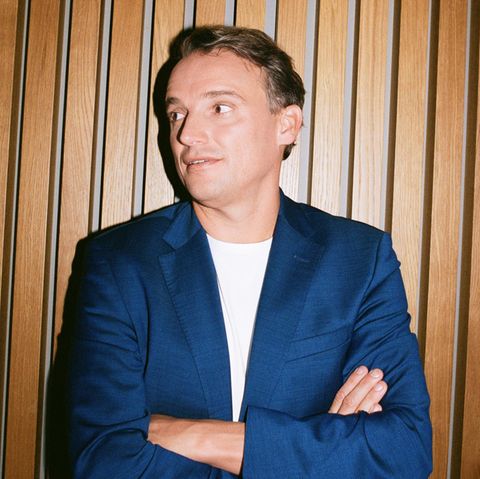 Christian Klein steht mit verschränkten Armen vor einer Wand