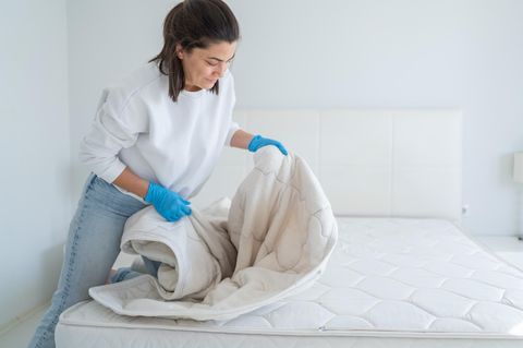 Dealnews: Eine Frau zieht einen Matratzenschoner auf die Matratze