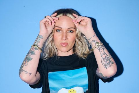 Evelyn Weigert steht vor blauem Hintergrund und trägt ein Pony-Shirt