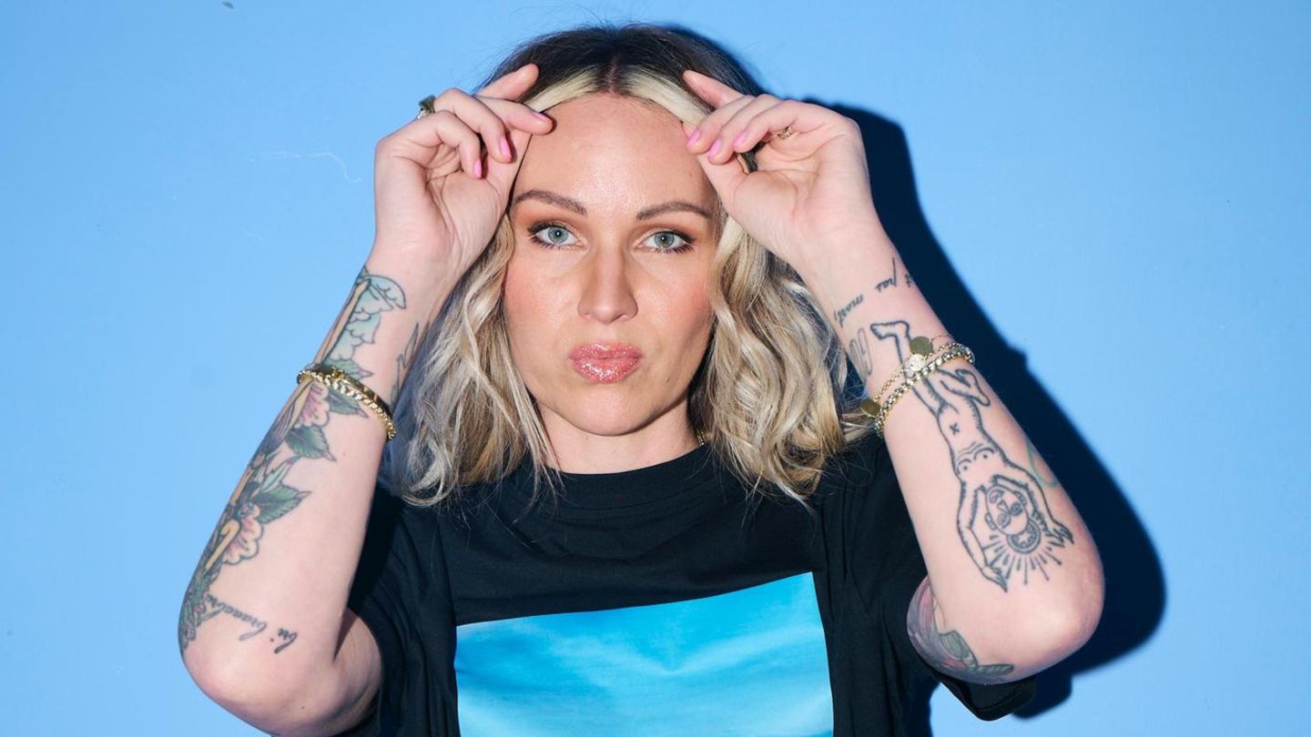 Evelyn Weigert steht vor blauem Hintergrund und trägt ein Pony-Shirt Evelyn Weigert steht vor blauem Hintergrund und trägt ein Pony-Shirt