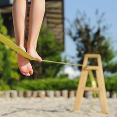 Slackline ohne Baum: Frau läuft am Strand über eine Slackline