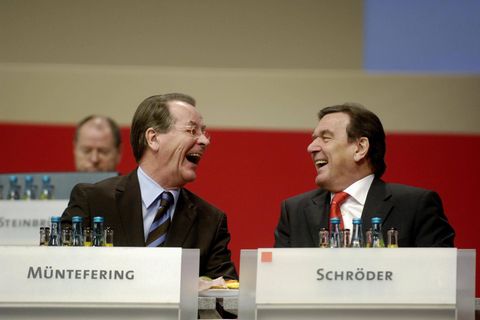 Gerhard Schröder (r.) und Franz Müntefering lachen auf dem Podium