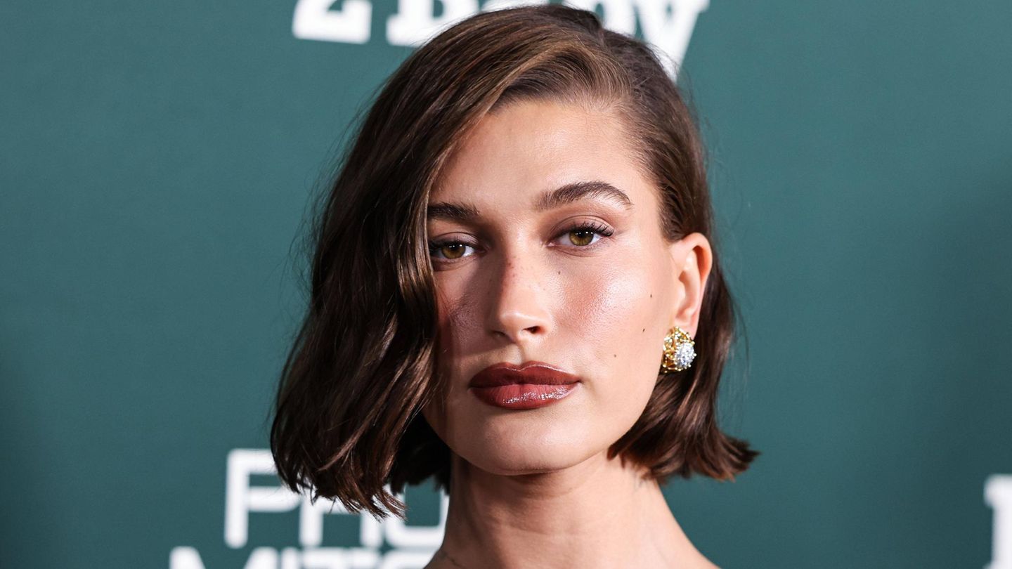 Hailey Bieber mit dunklem Haar-Bob vor grünem Hintergrund Hailey Bieber mit dunklem Haar-Bob vor grünem Hintergrund