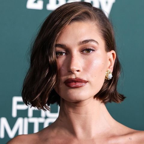 Hailey Bieber mit dunklem Haar-Bob vor grünem Hintergrund