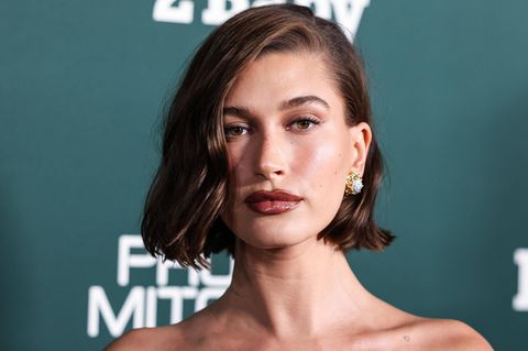 Hailey Bieber mit dunklem Haar-Bob vor grünem Hintergrund